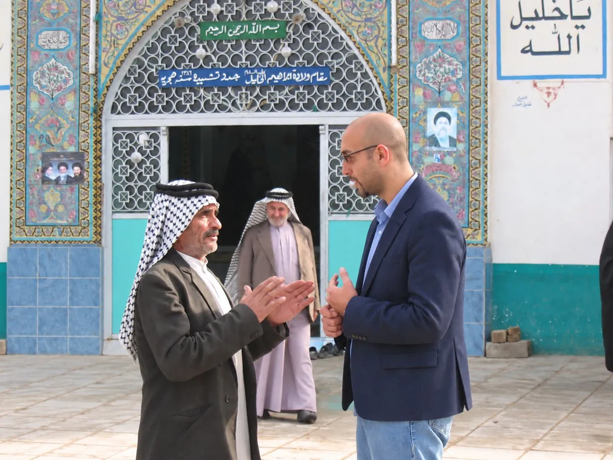 George Farag in conversation with an Iraqi man outside a tiled shrine, another man watching from the doorway